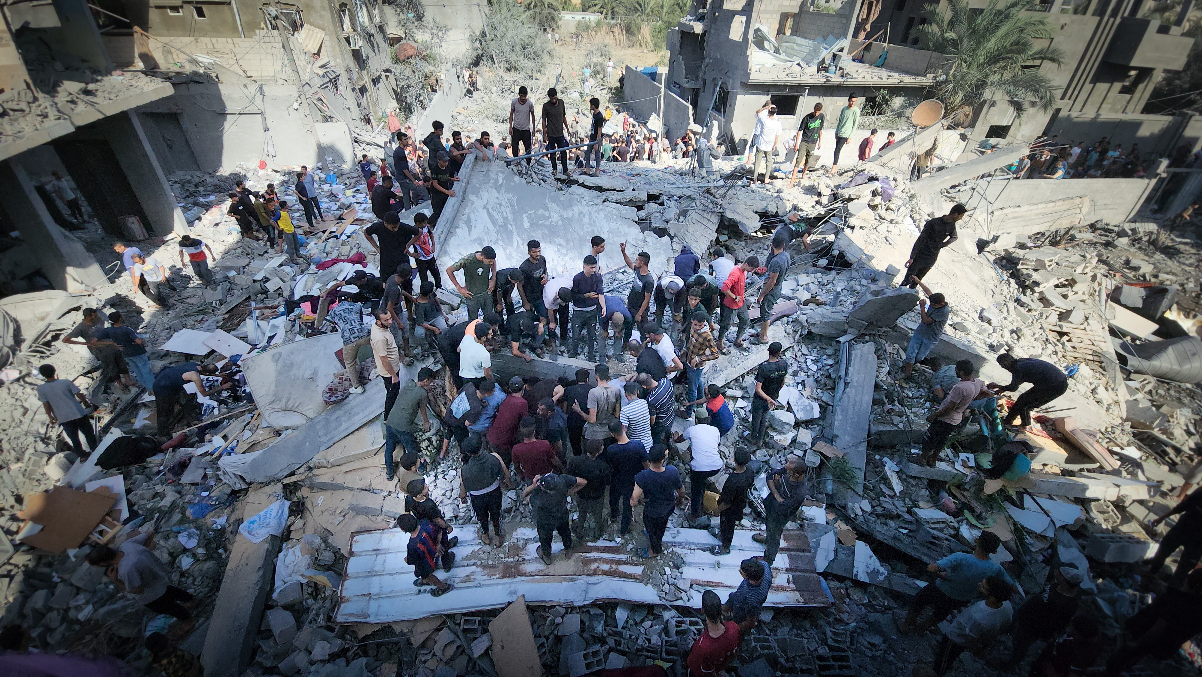 People stand in the rubble of a former building 