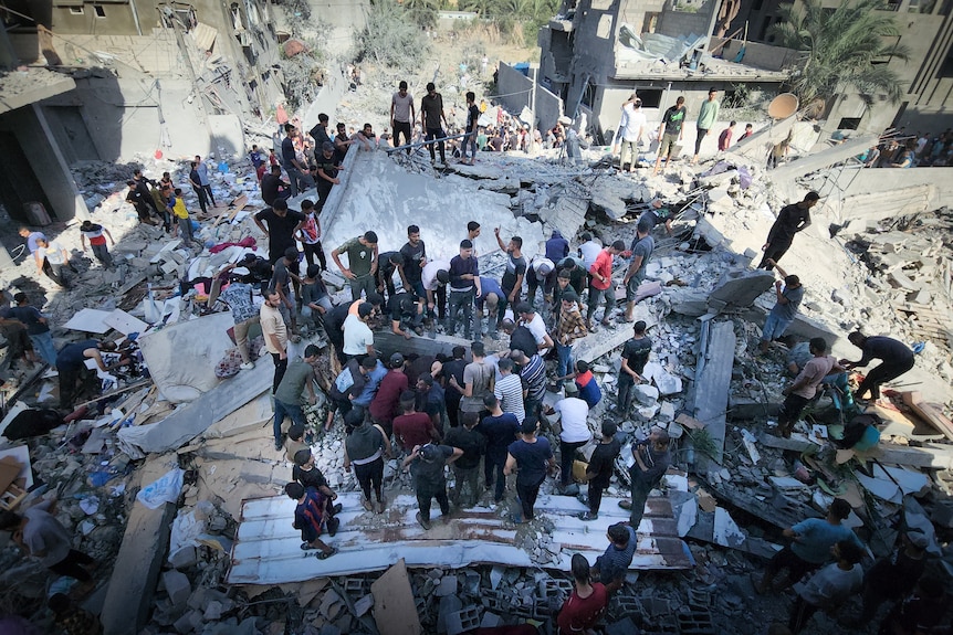 People stand in the rubble of a former building 