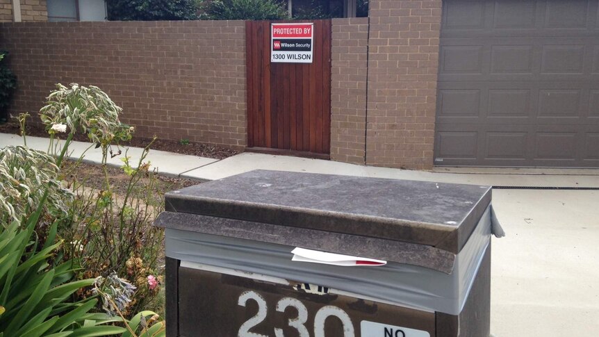 Taped-up letterbox and security sign on an empty Mr Fluffy asbestos-contaminated house.