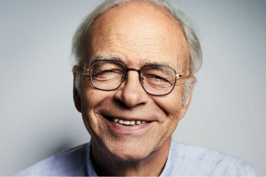 Closely cropped photo of Peter Singer with thinning grey hair, glasses and wide smile.