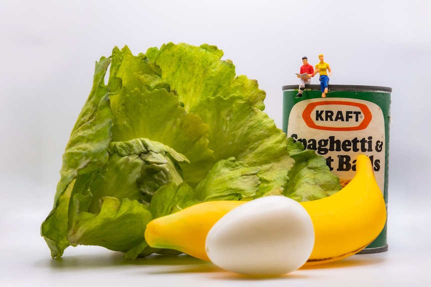 A photo of miniature people sitting on food.