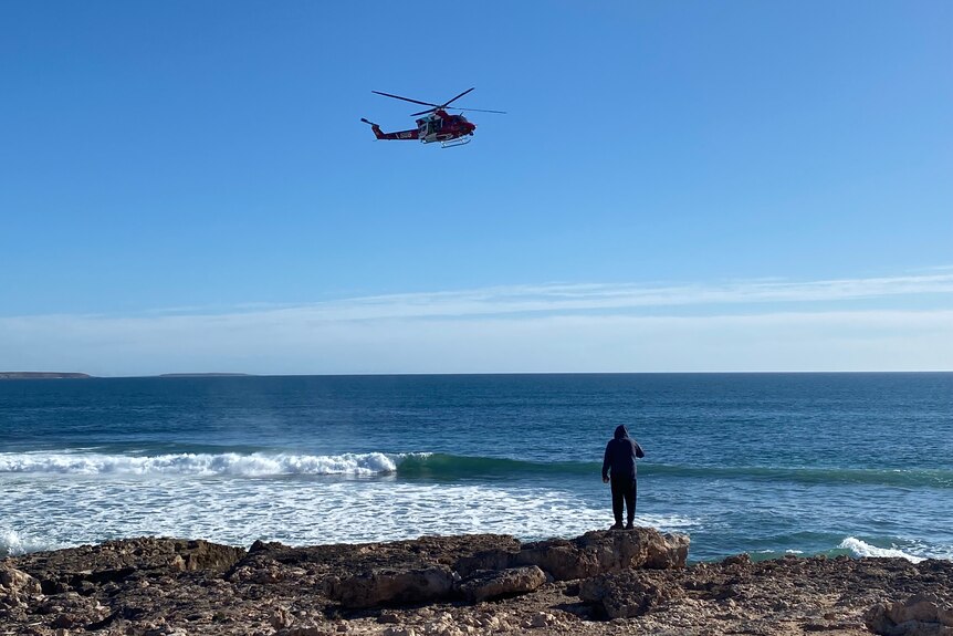 A search and rescue helicopter above a shoreline.