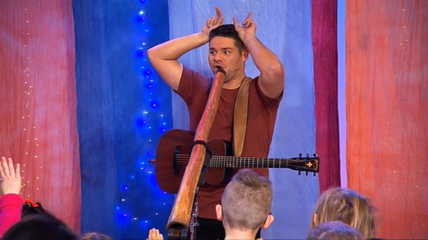 Singer with guitar and didgeridoo doing animal ears with his hands