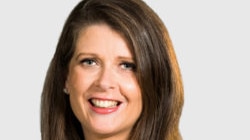 A portrait of Louise Higgins captures her smiling. The ABC chief financial officer is wearing red lipstick and a dark blouse.