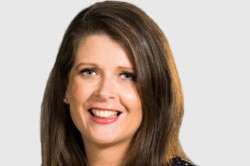 A portrait of Louise Higgins captures her smiling. The ABC chief financial officer is wearing red lipstick and a dark blouse.