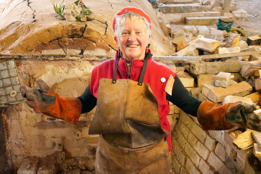 A woman wearing colourful safety gear stands in front of a Japanese kiln