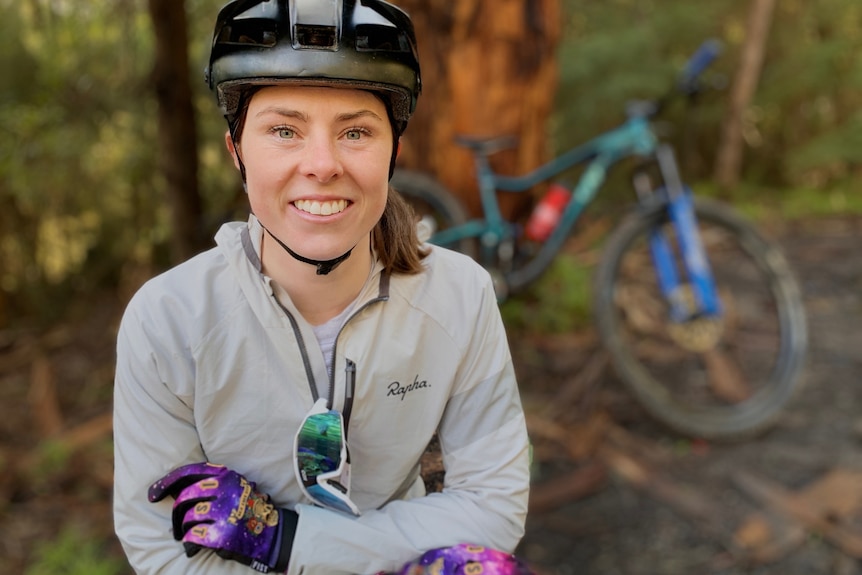 A photo of Rachel with a helmet and a bicycle in the background.