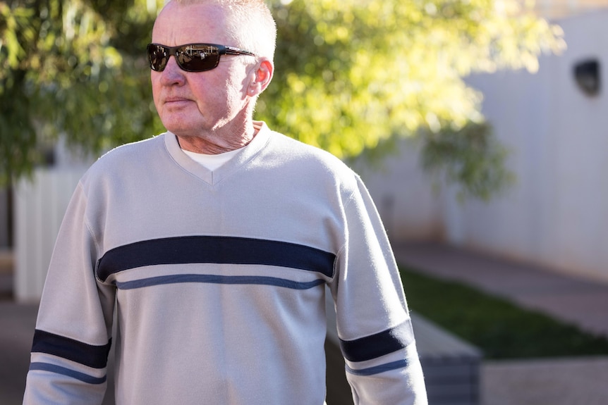 A man wearing sunglasses and a jumper outside courthouse.  