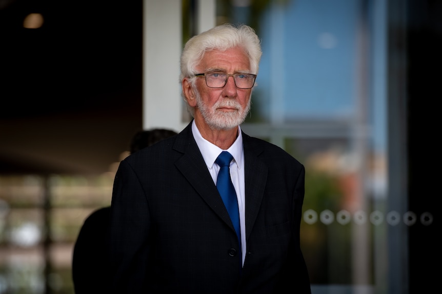 A serious-looking man in a suit walking out of the Northern Territory Supreme Court. 