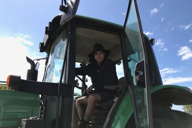 Carl Walker sits in his tractor with the side door open