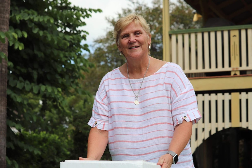 A woman smiling outside a large Queenslander house