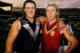 Former VFL/AFL players Tony Lockett and Dermot Brereton stand with arms around each others shoulder.