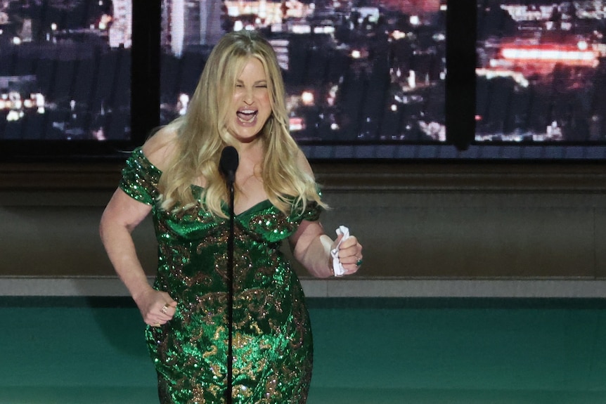 Jennifer Coolidge con vestido verde bailando sosteniendo un pañuelo en la mano