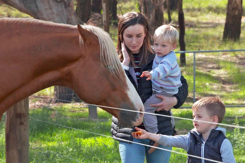 Bethany Kernaghan and her two children feed a horse.