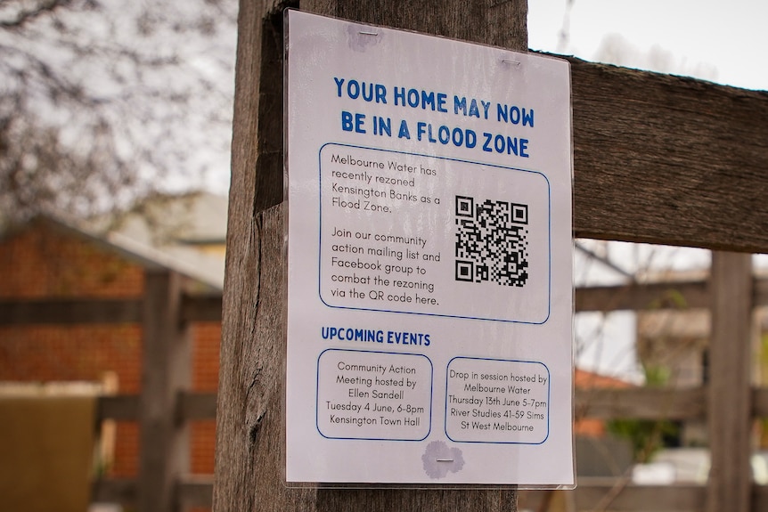 A sign for a community meeting is posted on a fence.