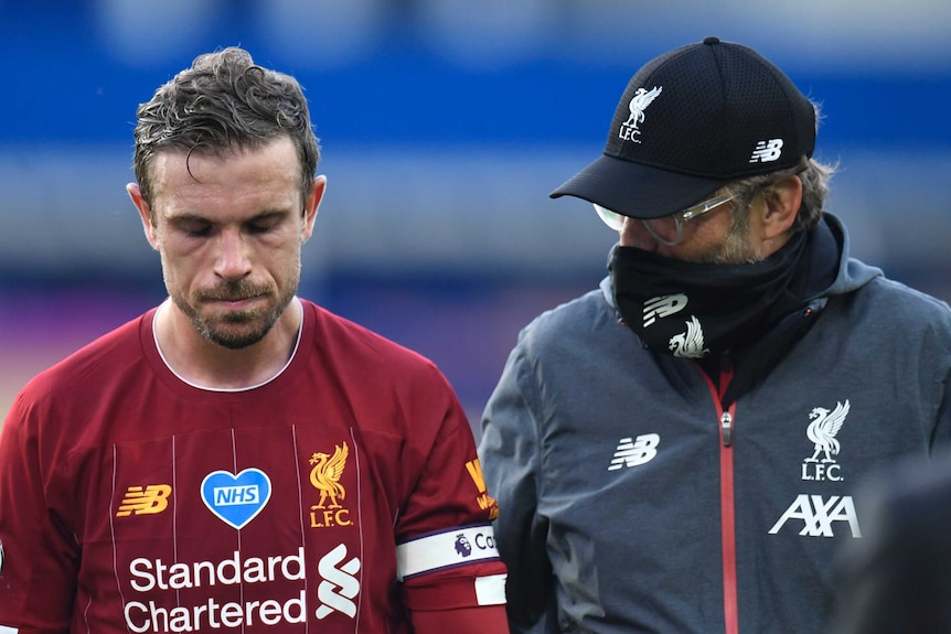 Liverpool player Jordan Henderson walks with manager Jurgen Klopp, wearing a mask, after a Premier League clash with Everton.
