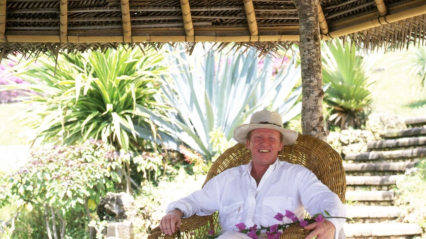 Made Wijaya sits in a straw chair in the garden of the four seasons hotel in Jimbaran Bay.
