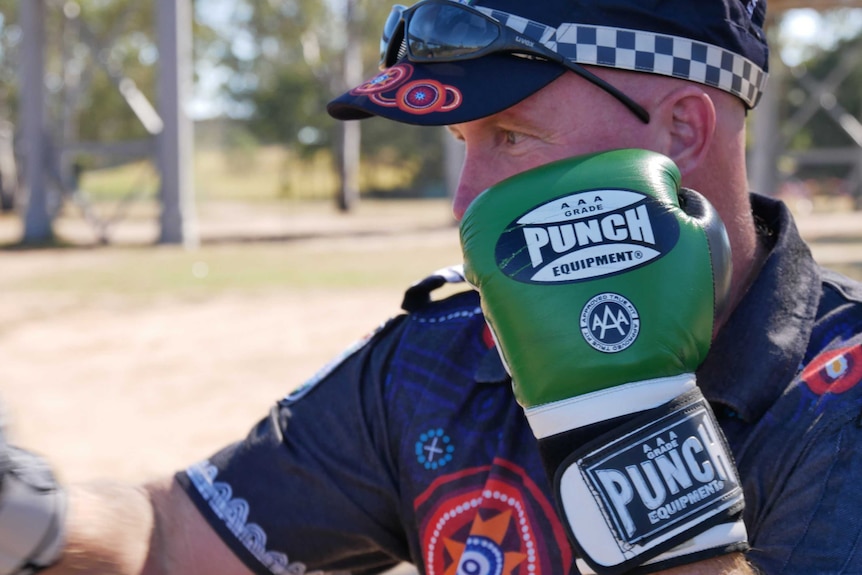 A Queensland police officer in an indigenous-themed uniform practices boxing in a park in Bundaberg.