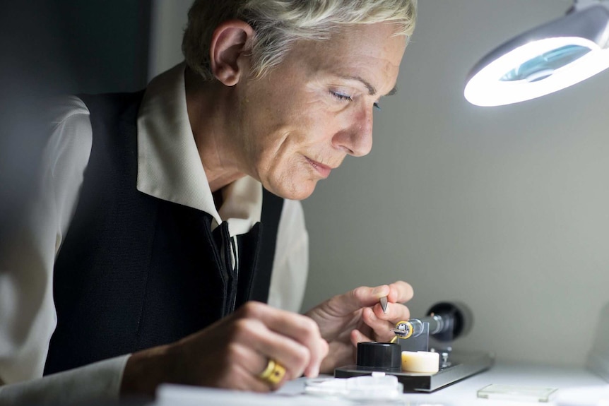 Scientist, Silvia Frisia examines a small object under a light.