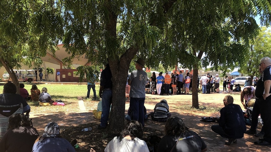 Residents gather under a shady tree during the protest.