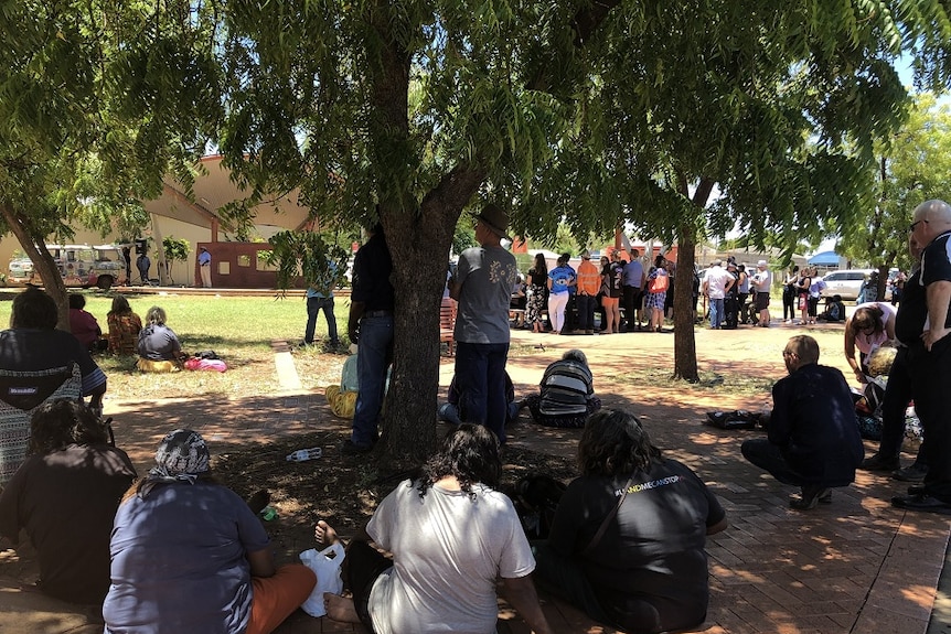Residents gather under a shady tree during the protest.