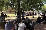 Residents gather under a shady tree during the protest.