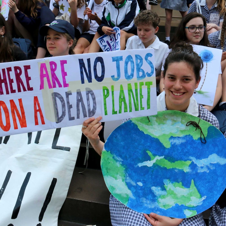 A school girl holds a sign saying: "There are no jobs on a dead planet".