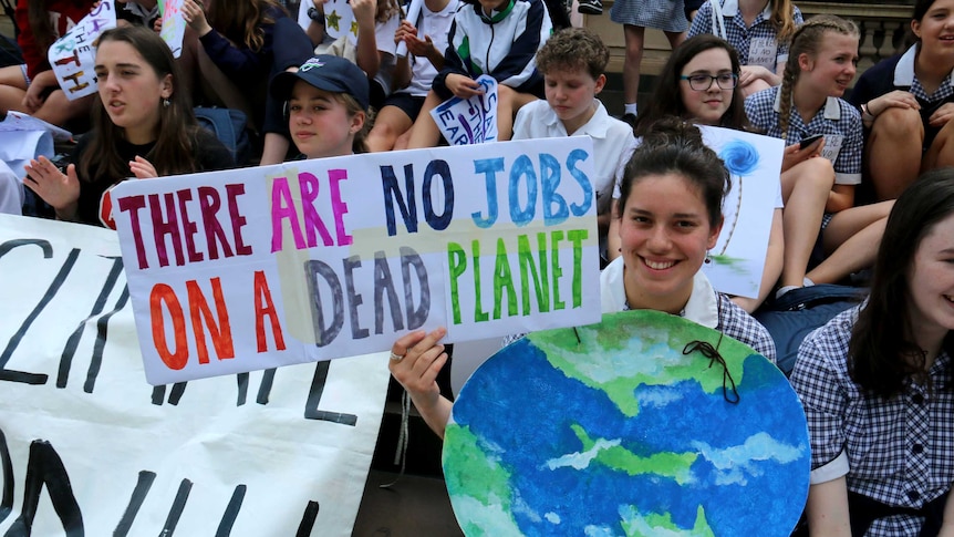 A school girl holds a sign saying: "There are no jobs on a dead planet".