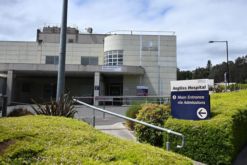 A sign points out the main entrance to Angliss Hospital, surrounded by short hedges.