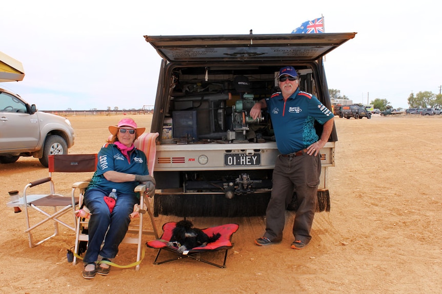 A couple leaning on the back of their ute, in the red outback sand of western Queensland.