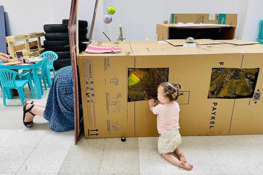 Mum climbs in box house with kid