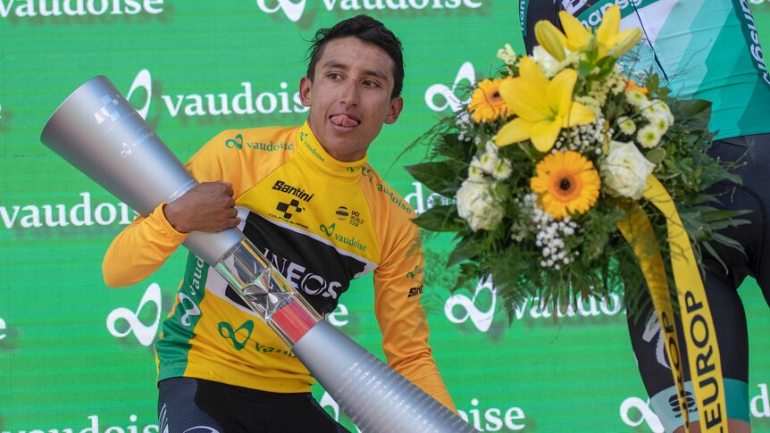 Egan Bernal holds a large silver trophy after winning the Tour de Suisse