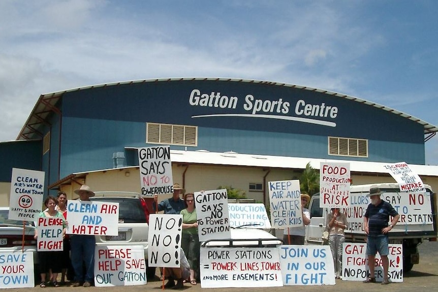 A group of eight residents stand with anti-power station placards outside the Gatton Sports Centre.