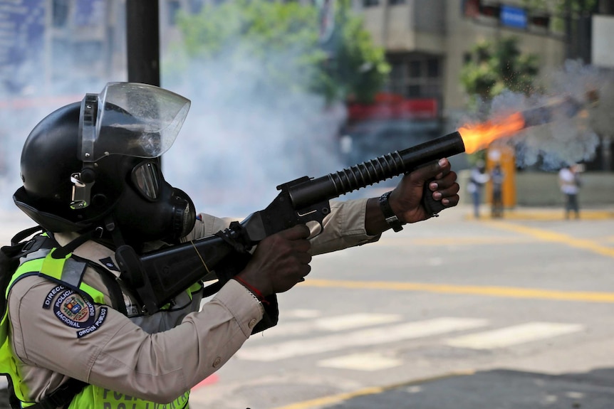 A police officer fires tear gas during Caracas protests