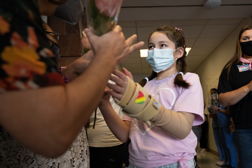 A young girl passes out roses as she leaves hospital. 