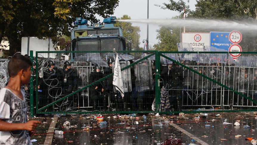 Hungarian riot police uses a water cannon against protesting migrants and refugees