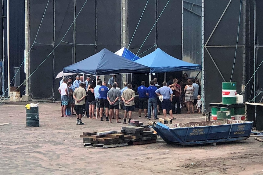 People gathered underneath a marquis at a marina for a memorial service