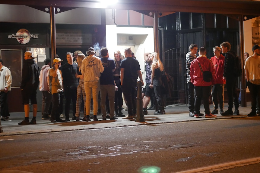 a group of people standing outside a nightclub