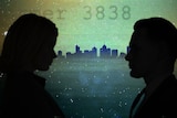 The silhouette of a woman and a man are shown in front of the Melbourne skyline.