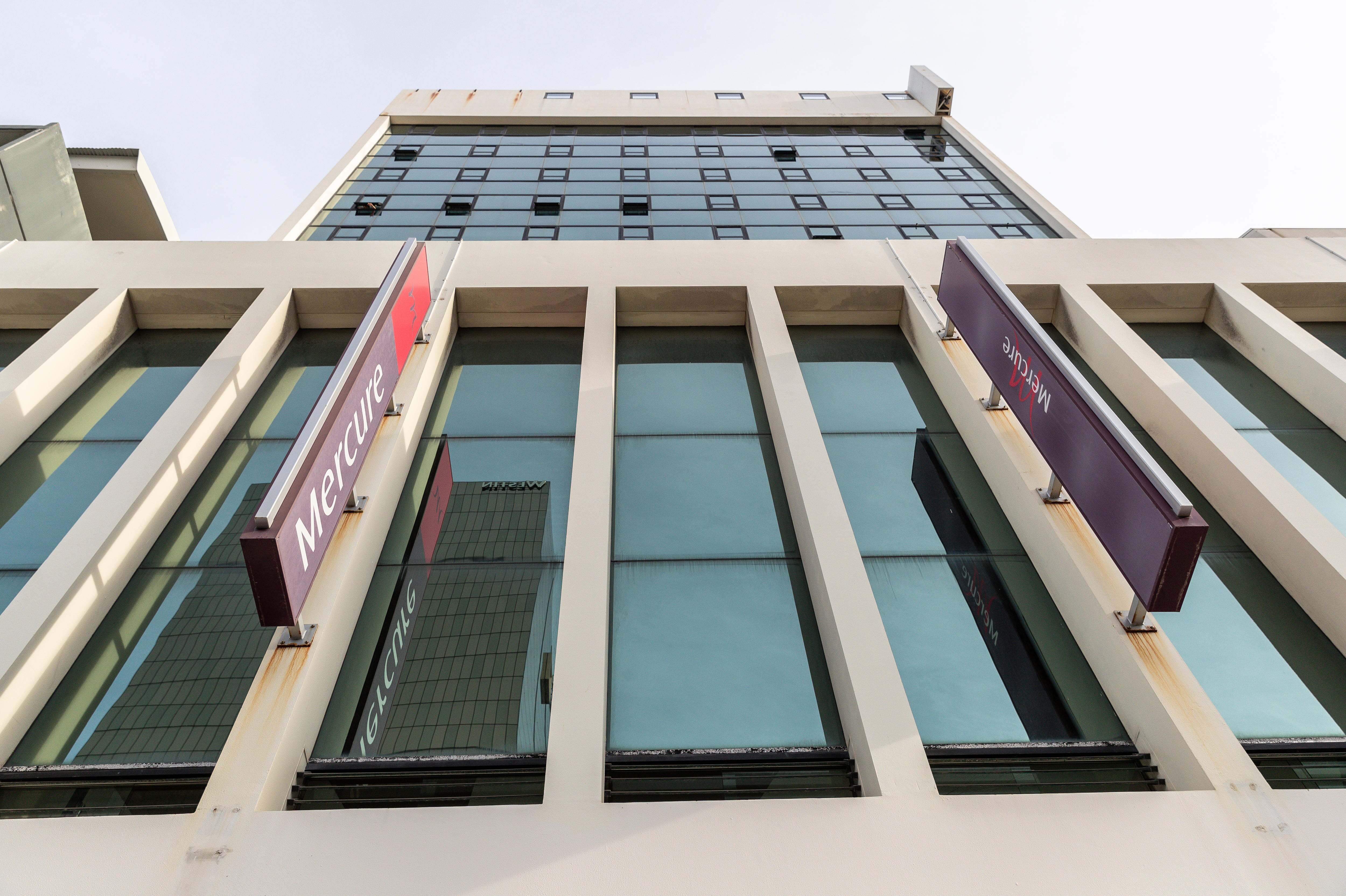 An angled shot of the exterior of the Mercure Hotel in Perth, looking upwards towards the sky.