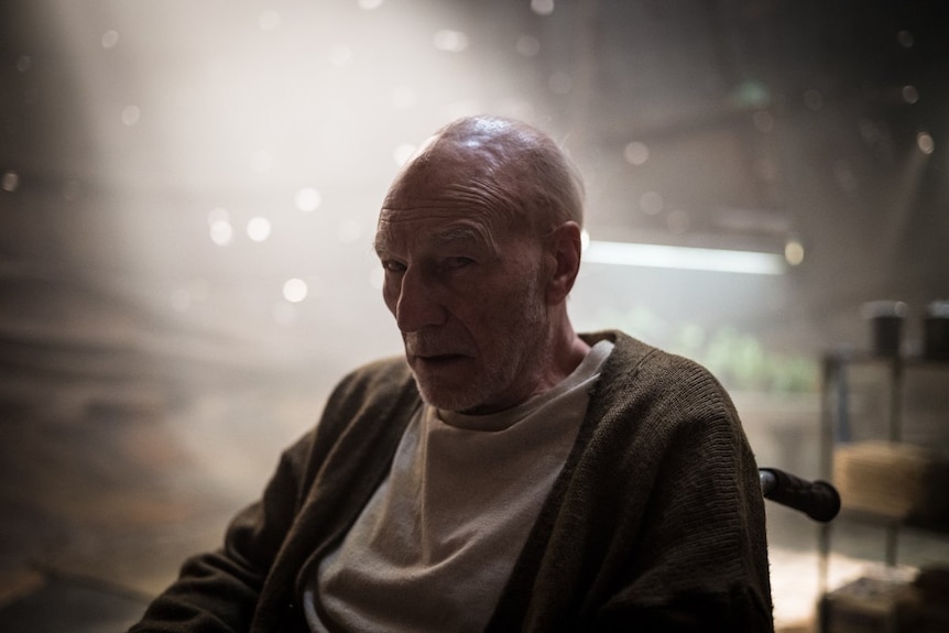 An old man looks tired and deceived in a dusty room.
