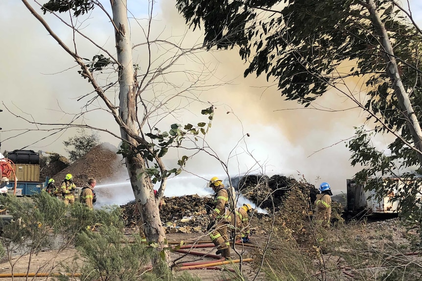 Firefighters fighting a fire at a trip in windy conditions.