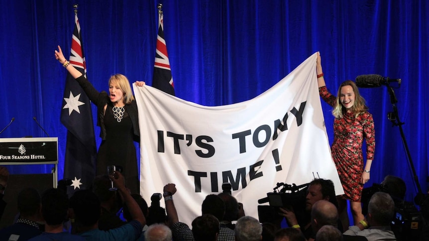 Liberal Party members celebrate with Tony Abbott banner.