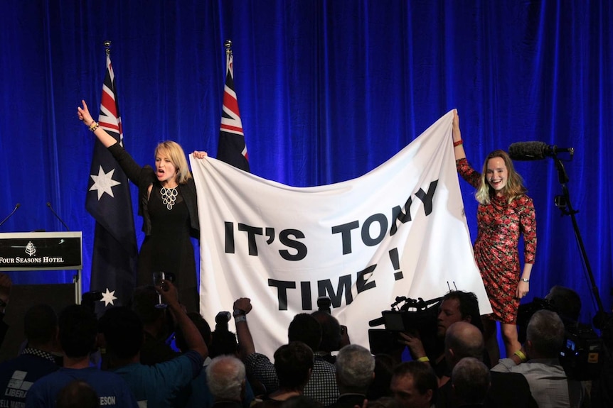 Liberal Party members celebrate with Tony Abbott banner.