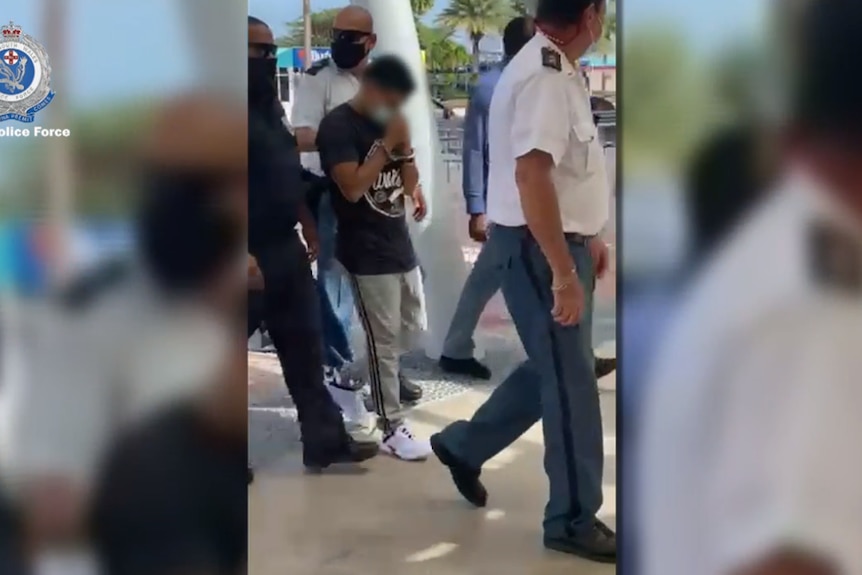 Young blurred man is escorted by police in a tropical setting