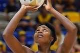 Mwai Kumwenda shoots for goal holding a netball above her head in both hands and looking up