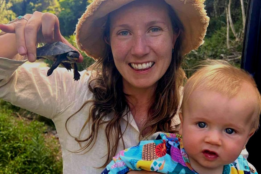 Woman holds an endangered turtle and her five month old baby