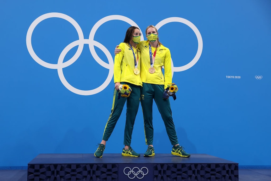 Les nageuses australiennes Emily Seebohm et Kaylee McKeown se tiennent bras dessus bras dessous l'une contre l'autre sur le podium olympique
