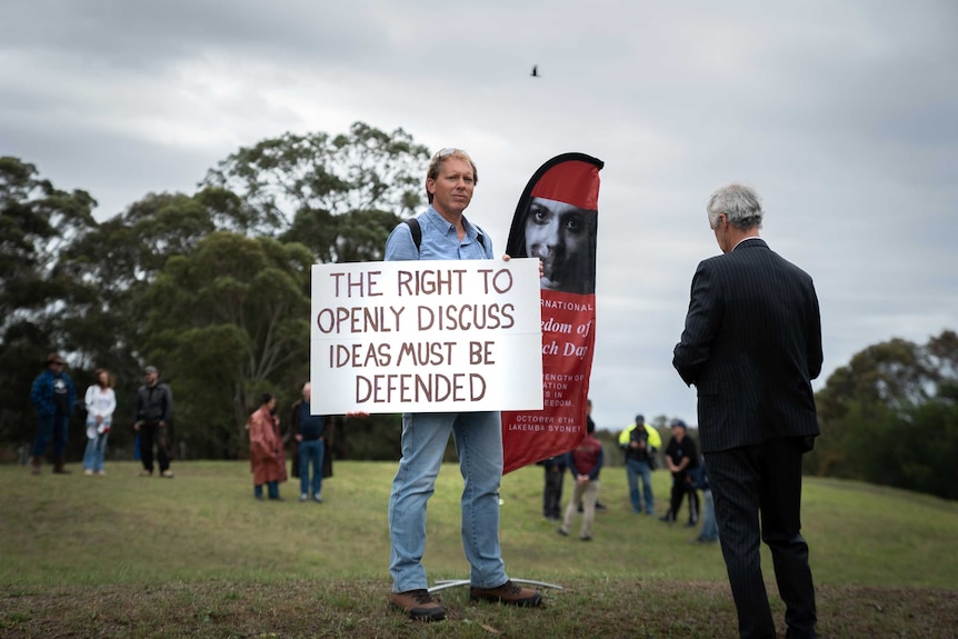 Man holds a sign at a freedom of speech rally organised by Blair Cottrell's lawyer