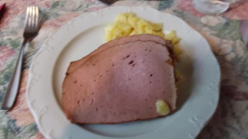 A plate with two slices of processed meat and scrambled egg.